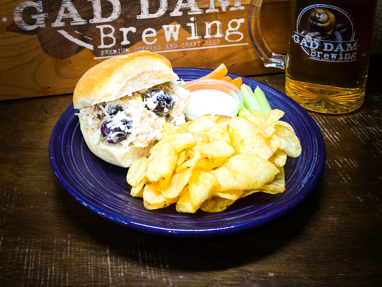 Fresh chicken salad sandwich with a side of chips and veggies.